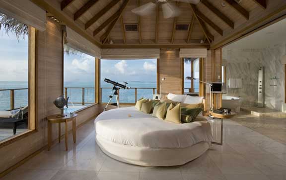 Sunset Water Villa with Pool at Conrad Maldives Rangali Island. This overwater villa is elevated on stilts and boasts a thatched roof.